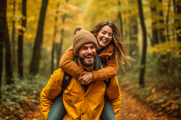 Happy couple piggybacking in a forest one autumn afternoon - obrazy, fototapety, plakaty