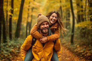 Fotobehang Happy couple piggybacking in a forest one autumn afternoon © Victor