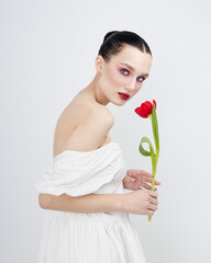 Sensual portrait of young attractive brenette woman holds of red tulips. Minimalist light pure photo shoot. Tenderness romantic. International Women's Day