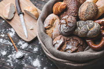 Delicious freshly baked bread inside a sack on wooden background