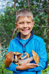 Portrait of cute boy with wild mushroom found in the forest