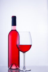 High glass with still rose wine and wine bottle