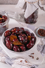 Bowl of pickled plums with spices on rustic wooden background. Clean eating, vegetarian food concept