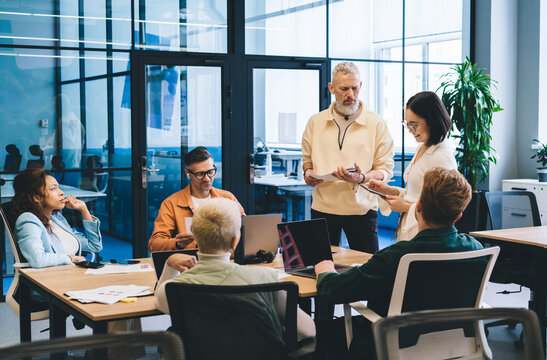 Group of experienced startuppers discussing business ideas during collaborative meeting for brainstorming in office interior, male and female employees with technology talking about trade project