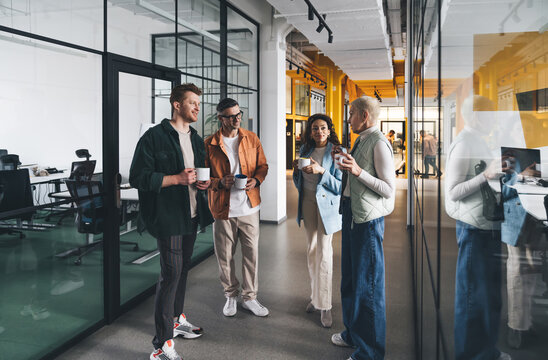 Diverse colleagues discussing ideas during break in office corridor - Powered by Adobe