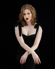 Fototapeta premium Beautiful redhead girl in black dress in front of black studio background