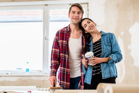 Portrait of a happy young couple wearing casual clothes while holding tools for home remodeling after moving in together