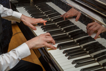 The hands of a person who is learning to play the piano under the guidance of a teacher.