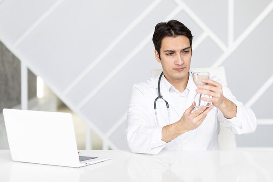 Close-up photo of physician holding hourglass. Time and health concept	