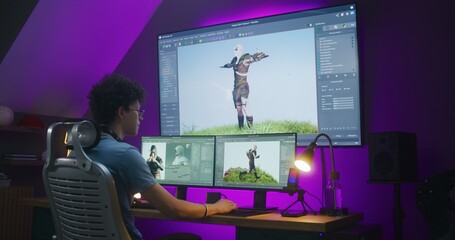 Young creative 3D designer creates video game character or animation, works remotely at home office. Computer and big digital screen with professional software interface for 3D modeling and design. © Framestock