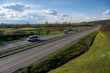 White modern delivery small shipment cargo courier van moving fast on motorway road to city urban suburb. White Modern comfortable tourist bus driving through highway. Travel and coach tourism concept