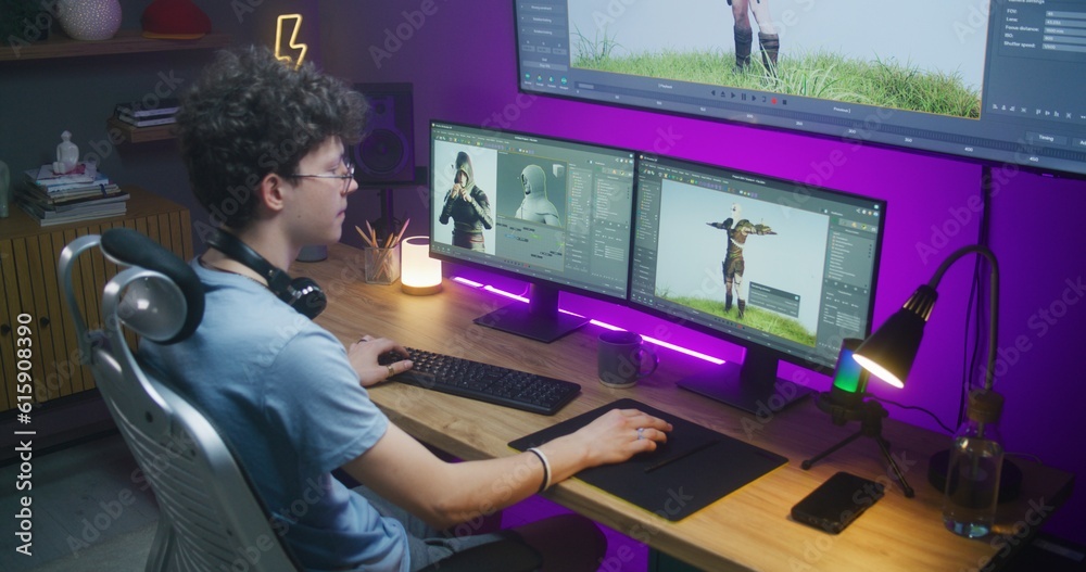 Wall mural young 3d designer draws video game character, creates animation. teenager works remotely at home on 