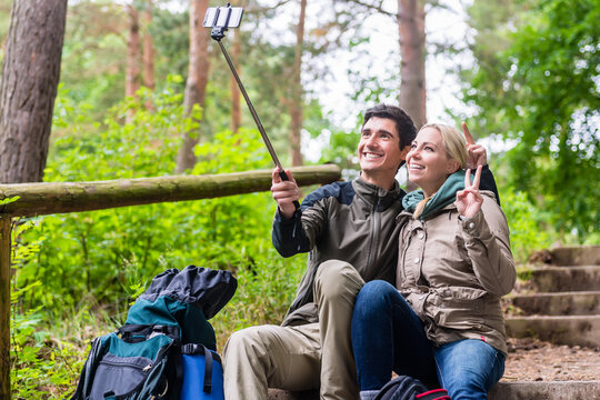 Man and woman hiking taking selfie with phone in nature