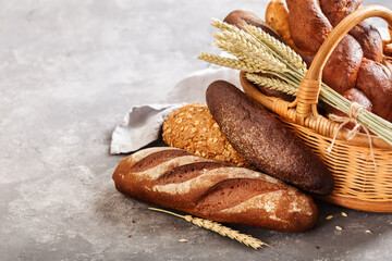 Different fresh bread in the basket on a grey background with copy space.