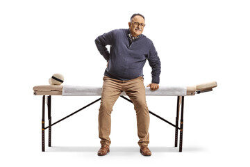 Mature man with a stiff back sitting at a massage table