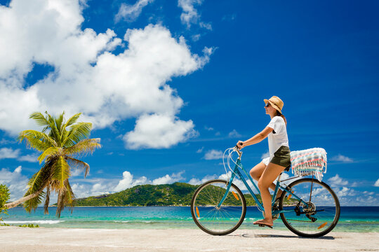 Woman on a bicycle ride along The Beach at Seychelles