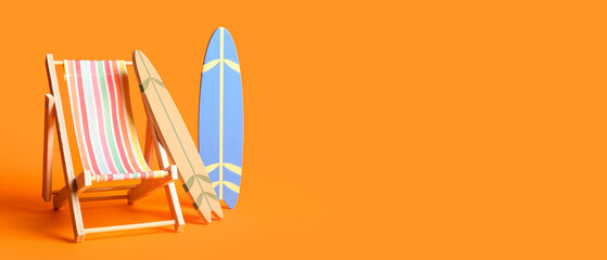 Small surfboards and deck chair on orange background with space for text