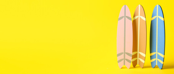 Small surfboards on yellow background with space for text