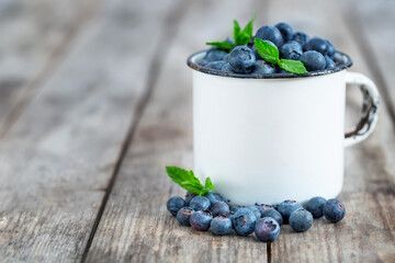 Fresh ripe blueberry in vintage mug on old wooden background