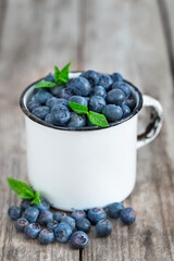 Fresh ripe blueberry in vintage mug on old wooden background