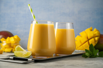 Mango smoothie in a glass with fresh mango, mint and lime.