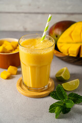 Mango smoothie in a glass with fresh mango, mint and lime.