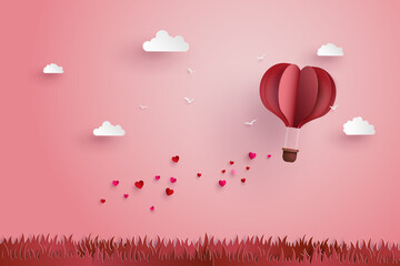 illustration of love and valentine day,Origami made hot air balloon fly over grass with heart float on the sky.paper art style.