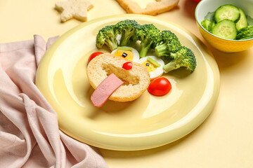 Plate with funny breakfast in shape of face and vegetables on beige background