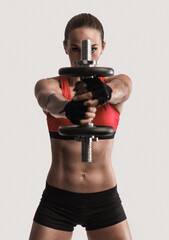 Fototapeta na wymiar Beautiful young woman in a workout gear lifting dumbbells
