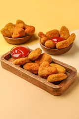 Wooden board with tasty nuggets and ketchup on color background