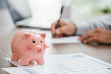 Financial consultant working at office desk and piggy bank on the foreground: insurance, home and...