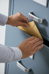 Businessman putting a closed envelope into a filing cabinet's drawer, data archive and protection concept