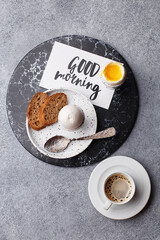 Continental breakfast with soft boiled eggs, slice of bread and freshly brewed coffee over gray concrete background. Top view, flat lay