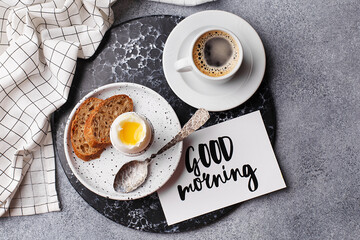 Continental breakfast with soft boiled egg, slice of bread and freshly brewed coffee over gray concrete background. Top view, flat lay - obrazy, fototapety, plakaty