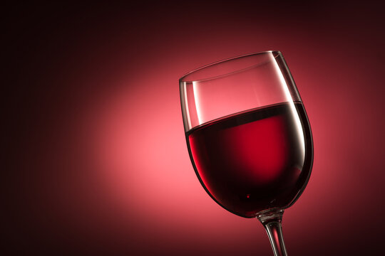 Red wine in a wineglass on red background, wine tasting, luxury and celebration concept