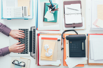 Businessman working at his full office desk and typing with a laptop, business and technology concept © Designpics