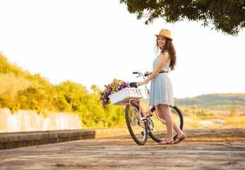 A beautiful young woman with her bicycle full of wildflowers