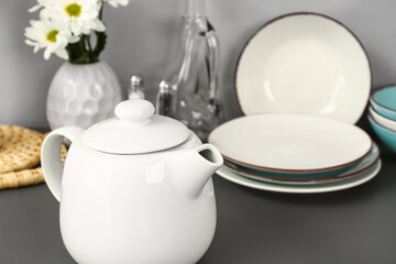 Teapot with different kitchen stuff on black table