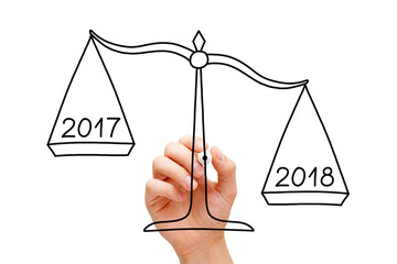 Hand drawing scale concept with marker on transparent wipe board isolated on white. Year 2018 is better than 2017.