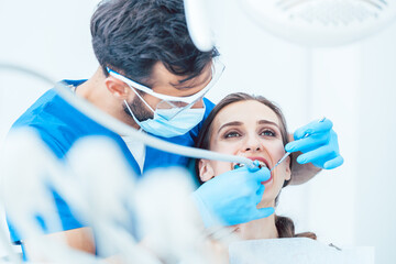 Young woman during painless oral treatment in the modern dental clinic led by an experienced dentist