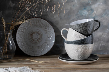 Ceramic mugs and plate on wooden table