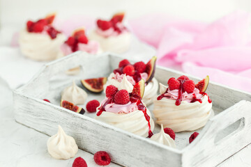 Delicious mini Pavlova meringue cake decorated with fresh raspberry, figs  and berry sauce on white background