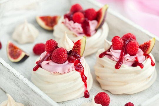 Delicious mini Pavlova meringue cake decorated with fresh raspberry, figs  and berry sauce on white background