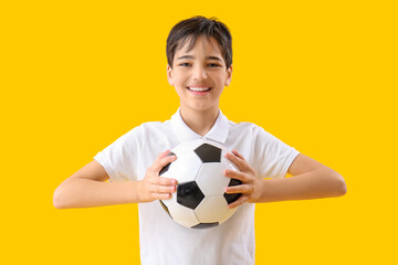 Little boy with soccer ball on yellow background