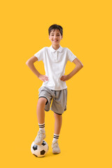 Fototapeta na wymiar Little boy with soccer ball on yellow background