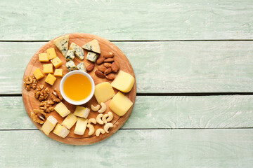 Pieces of tasty cheese, nuts and honey on light wooden background