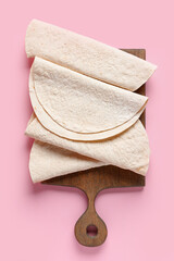 Board with thin lavash on pink background