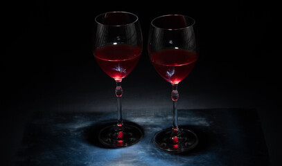 Pair of wine glasses with red wine on a dark background.