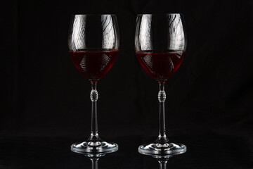 Two wine glasses with red wine on a dark background.