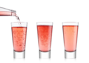 Pouring pink soda lemonade from bottle to glass on white background